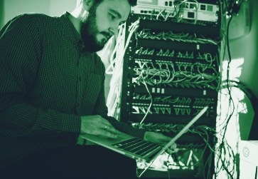 Engineer working at a network cabinet with a laptop